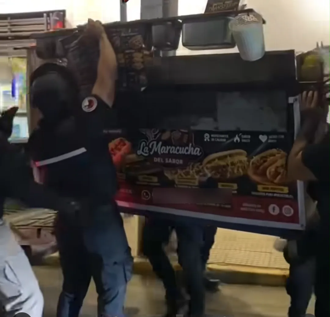 Funcionarios cargan entre varios un carro de comida con el letrero La Maracucha del Sabor